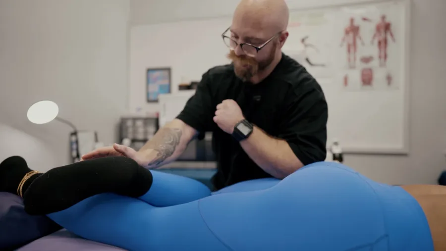 Practitioner stretching a client's leg on a treatment table