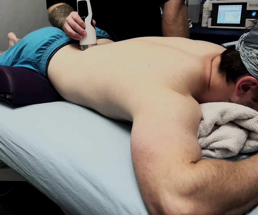 Handheld therapy device applied to a client's back on a treatment table